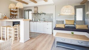 A modern kitchen with white cabinets, a wooden island, and hanging pendant lights. - The Beach House - Studios & Suites (Javea)