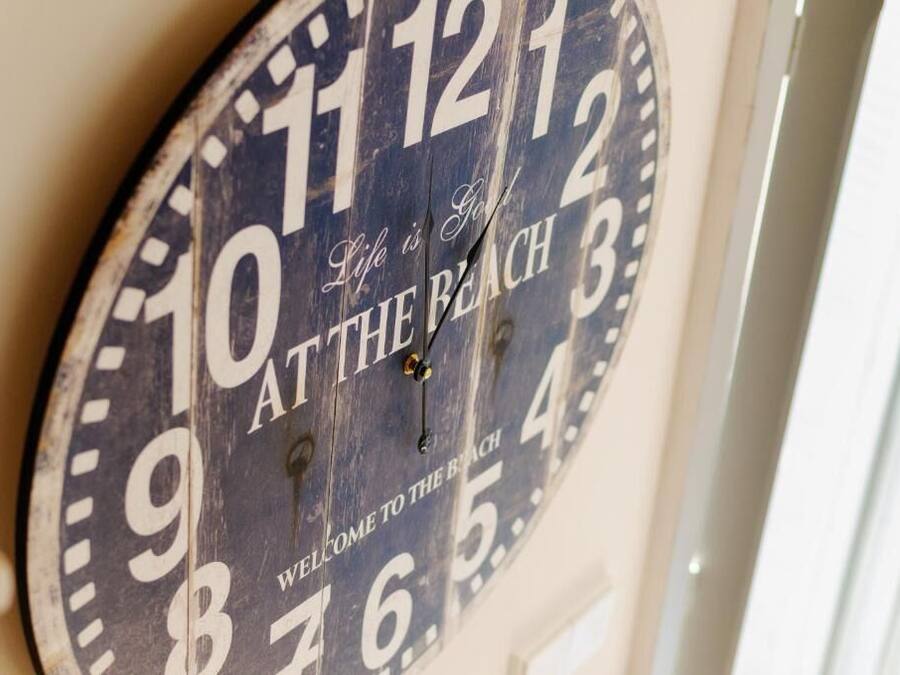 A wall clock with the text "Life is God" and "Welcome to the Beach" on it.