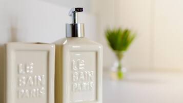 Two white perfume bottles with pumps, labeled "LE BAIN PARIS" on a clean surface.