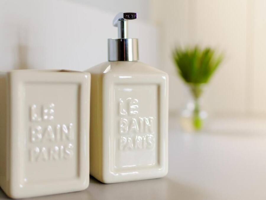 Two white perfume bottles with pumps, labeled "LE BAIN PARIS" on a clean surface.