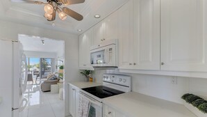 Una cucina moderna con mobili bianchi, un forno a microonde integrato, un piano cottura e una ventola a soffitto.