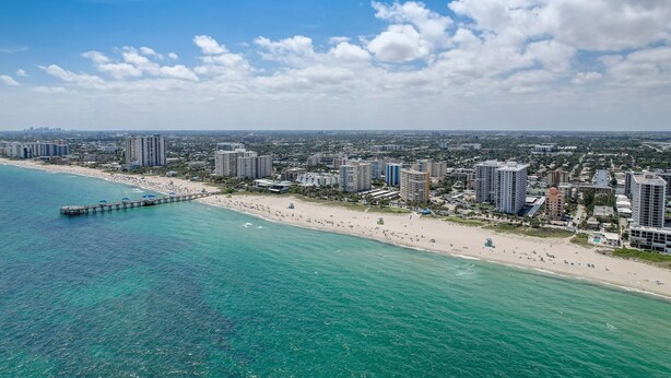 Una vista aerea di una città costiera con spiaggia, molo e grattacieli.