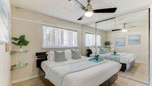 Una camera da letto con un letto grande, una ventola a soffitto, una finestra e uno specchio.