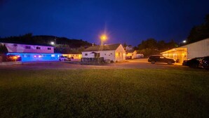 A parking lot with several cars, a building with a flat roof, and a grassy area. - Gateway Motel (Minnedosa)