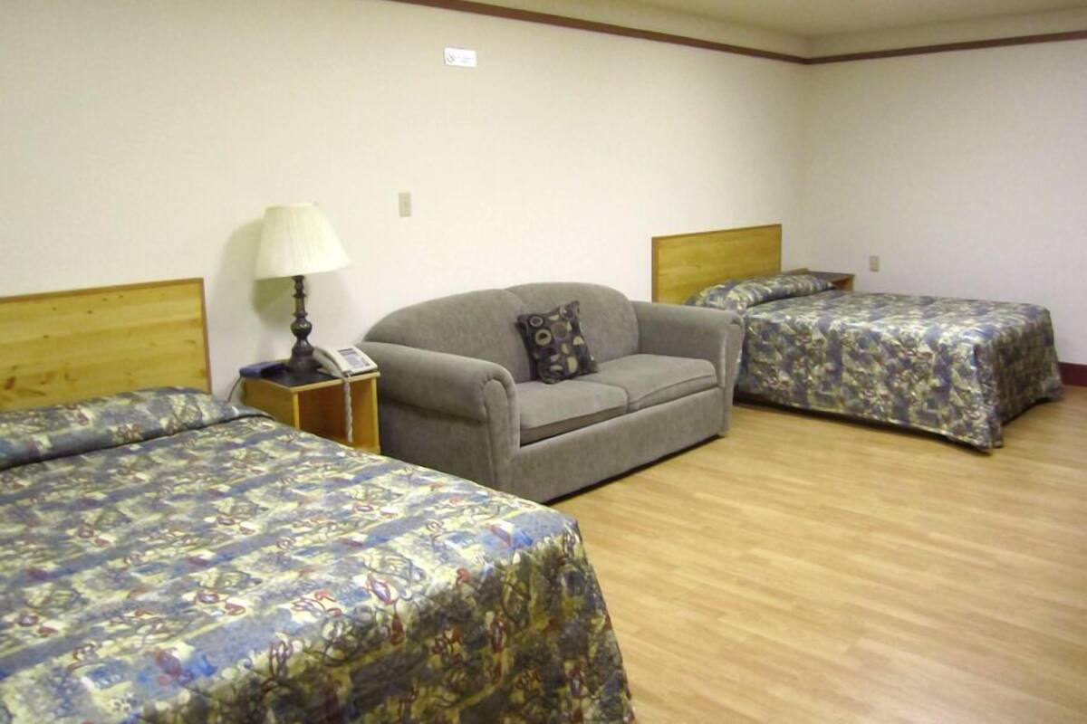 A room with two beds, a sofa, a lamp, and a telephone.