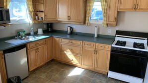 A kitchen with wooden cabinets, a stove, a sink, and a refrigerator. - Gateway Motel (Minnedosa)