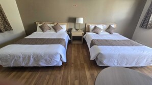 A hotel room with two beds, a bedside table with a lamp, and a round table. - Gateway Motel (Minnedosa)