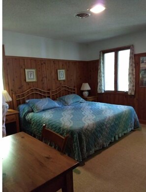 Cozy retreat with a comfortable bed, wooden nightstand, and a window with curtains.