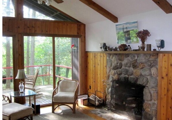 Cozy cabin with a fireplace, balcony, and forest views.