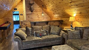 A cozy cabin interior with a wooden ceiling, a sofa set, a fireplace, and a mounted deer head. - Best Lake in Southwest Michigan! Pontoon Boat included. Private beach frontage. (Grand Junction)