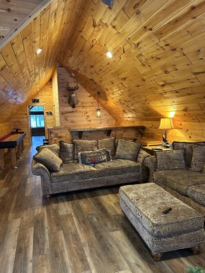 A cozy cabin interior with a wooden ceiling, a sofa set, a fireplace, and a mounted deer head. - Best Lake in Southwest Michigan! Pontoon Boat included. Private beach frontage. (Grand Junction)