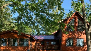 A wooden cabin with a porch and a grassy yard. - Best Lake in Southwest Michigan! Pontoon Boat included. Private beach frontage. (Grand Junction)
