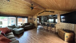 Une cabane en bois spacieuse comprenant un salon, une cuisine et un coin bar.