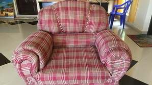 A red and white plaid sofa with a chain strap, positioned on a tiled floor with a black and white checkered pattern.