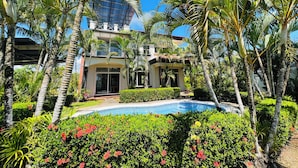 A modern house with a pool surrounded by lush greenery and palm trees. - 3-BR Villa, 5 min to Beach, AC, WiFi, Private Pool & Rancho, Esterillos Este (Esterillos Este)