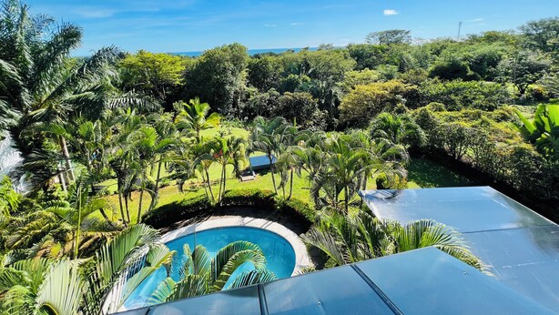 A lush landscape with a swimming pool surrounded by tropical vegetation and a clear blue sky. - 3-BR Villa, 5 min to Beach, AC, WiFi, Private Pool & Rancho, Esterillos Este (Esterillos Este)
