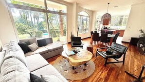 A spacious living area with a large sofa, a coffee table, and a dining area with chairs and a table. - 3-BR Villa, 5 min to Beach, AC, WiFi, Private Pool & Rancho, Esterillos Este (Esterillos Este)