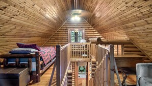 Een vakantiehuis in blokhutstijl met een slaapkamer op de entresol, een trap en uitzicht op de natuur.