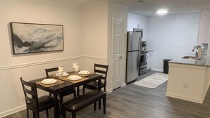 A dining area with a dark wooden table set for four, a bench, and a painting on the wall. - Fabulous Fully-Furnished Apartment in Alpharetta (Alpharetta)