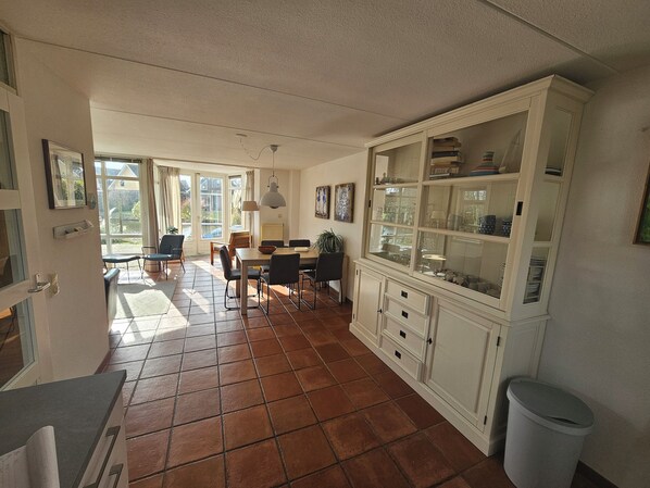 A spacious kitchen with a dining area, large windows, and a tiled floor.
