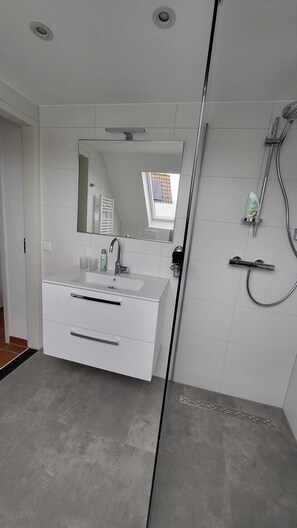 Een bad/douchecombinatie, een haardroger, handdoeken, toiletpapier