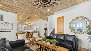Ein modernes Wohnzimmer mit einem schwarzen Ledersofa, einem Couchtisch aus Holz mit Pflanzen und einem großen Spiegel an der Wand.