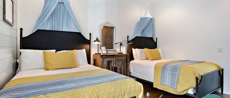 Un dormitorio con dos camas, cada una con dosel, una mesita de noche con lámpara y un espejo.