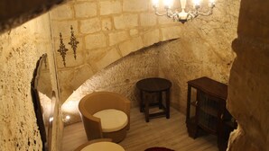 A rustic stone-walled room with a wooden chair, a small table, and a chandelier. - Palazzino Nina Boutique Hotel (Qormi)