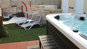 A hot tub with a wooden deck, a small pool, and a stone wall. - Palazzino Nina Boutique Hotel (Qormi)