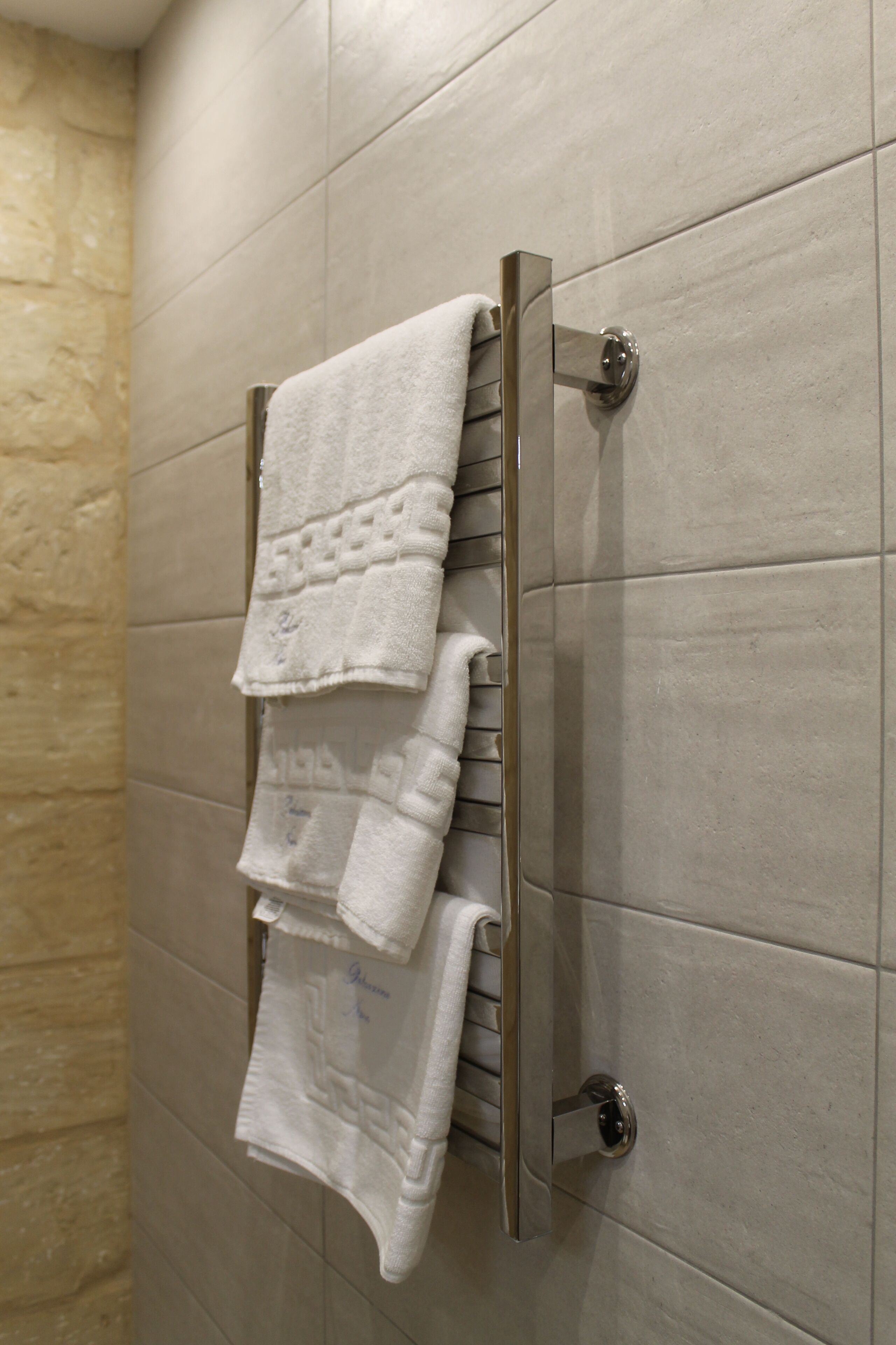 Un baño con un perchero que sostiene varias toallas blancas.