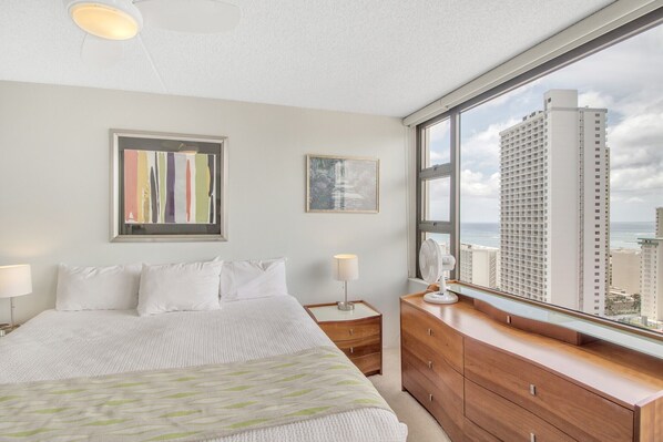 Een hotelkamer met een groot bed, een dressoir, een nachtkastje en een raam met uitzicht over de stad.