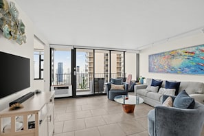 A modern living room with a flat-screen TV, a glass coffee table, and a sofa set.