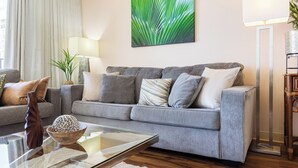 A modern living room with a grey sofa, a glass coffee table, and a decorative bowl.