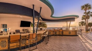 A curved bar area with seating, a flat-screen TV, and a tiled floor.