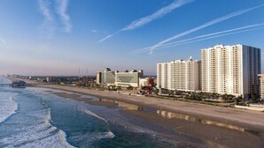 A coastal hotel with multiple high-rise buildings, beachfront access, and a pier.