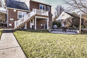 A two-story brick house with a front porch, a covered patio, and a small garden area. - The Loft at Riverside (Lancaster)