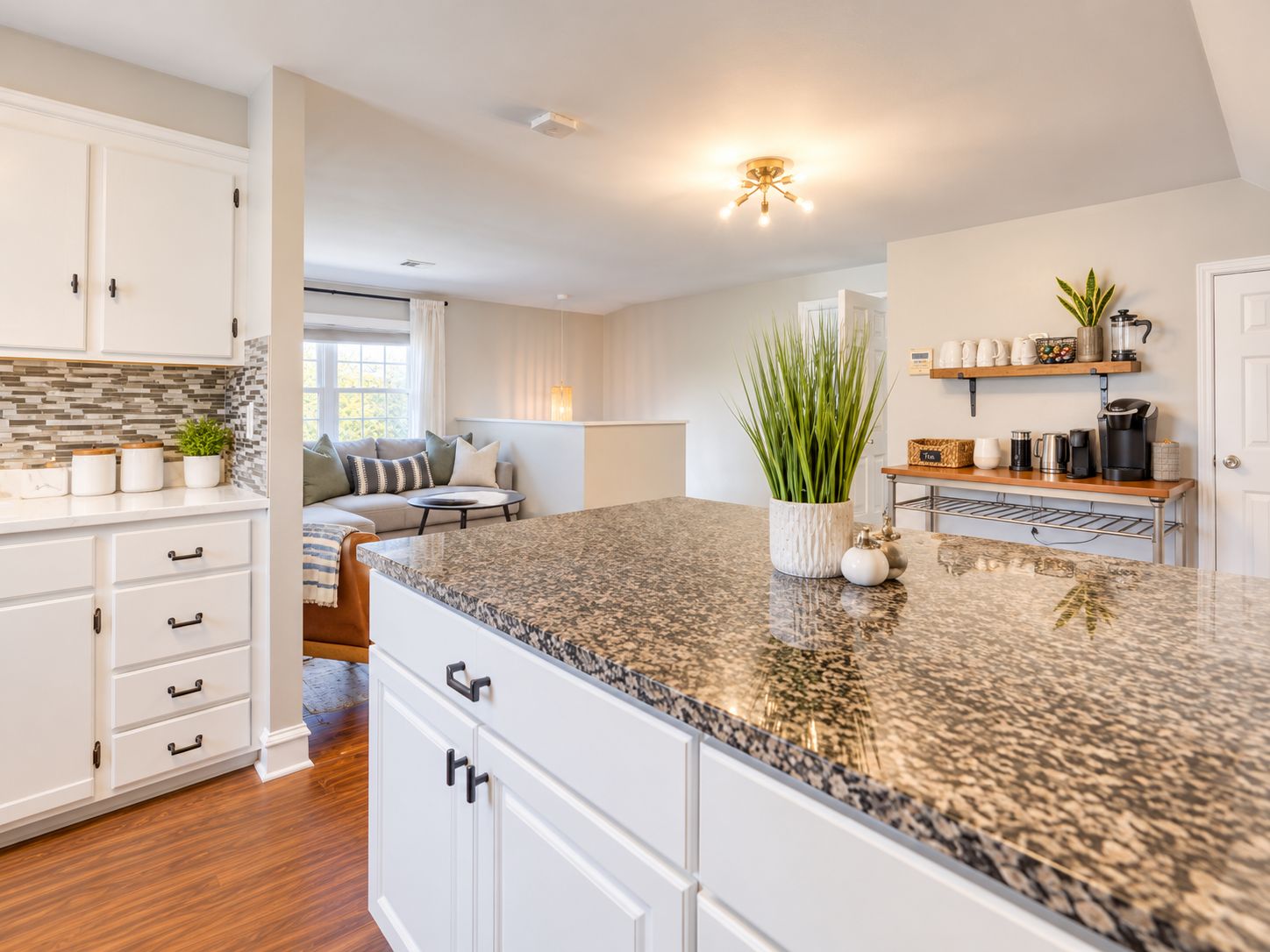 A modern kitchen with granite countertops, white cabinetry, and a central island.