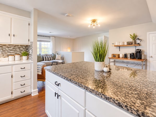A modern kitchen with granite countertops, white cabinetry, and a central island.