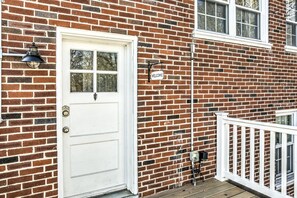 A white front door with a glass panel, a 'WELCOME' sign, and a white railing on a brick house. - The Loft at Riverside - King Bed + Deck + Coffee Bar (Lancaster)