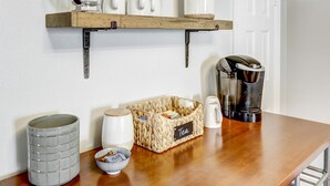 Eine Küchenarbeitsplatte mit Kaffeemaschine, Wasserkocher, Teekocher und einem Korb mit der Aufschrift 'Tee'.