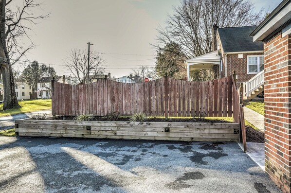 A wooden fence with a stop sign, a brick house, and a driveway.