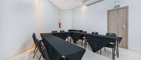 Una sala de conferencias con una larga mesa, sillas, un equipo de aire acondicionado y un extintor.
