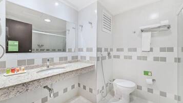 A modern bathroom with a granite countertop, a white sink, a toilet, and a shower area.