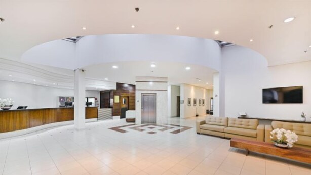 A spacious lobby with a reception desk, a seating area, and a large wall-mounted TV. - Hotel Nacional Inn Cuiabá (Cuiabá)