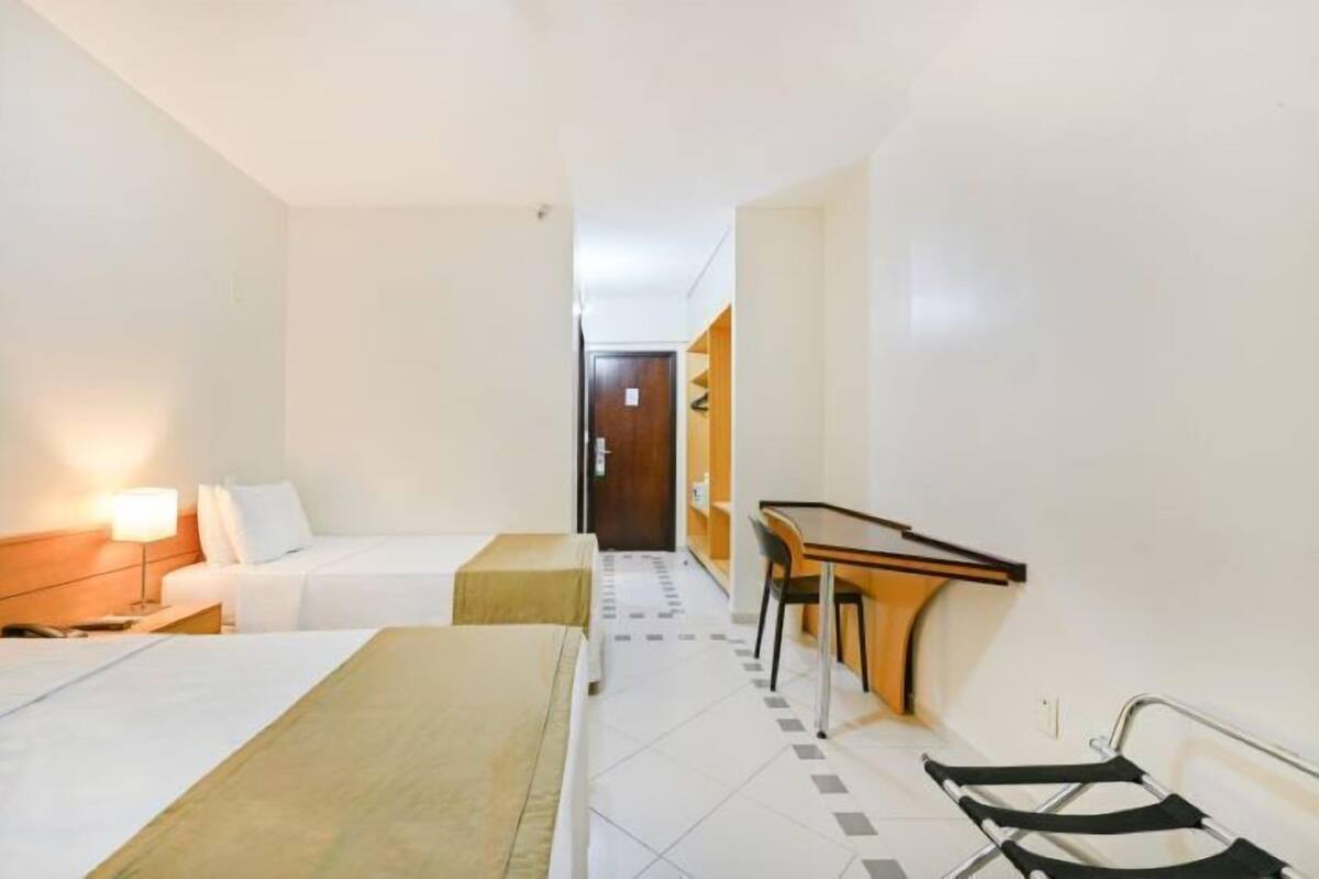 A hotel room with two beds, a desk, and a chair.