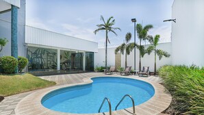 A swimming pool with a tiled deck, surrounded by palm trees and lounge chairs. - Hotel Nacional Inn Cuiabá (Cuiabá)