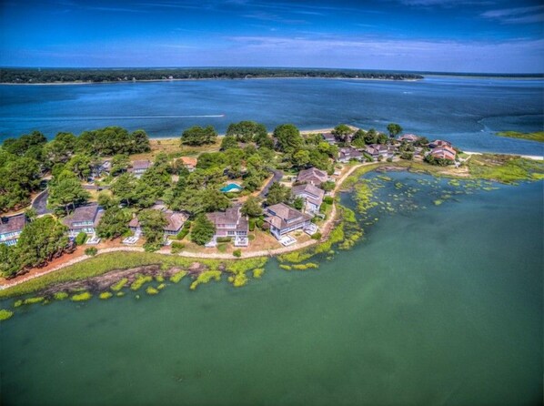An aerial view of a residential area with houses surrounded by water and greenery.