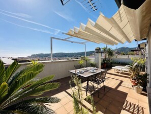 A rooftop patio with a table set for dining, surrounded by potted plants and a view of the city and hills. - Llevant CostaBravaSi - Terrace, views, AC (Sant Feliu de Guíxols)