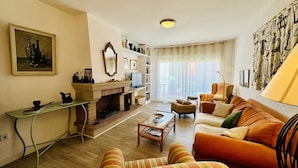 A living room with a sofa, armchairs, a coffee table, a fireplace, and a television.