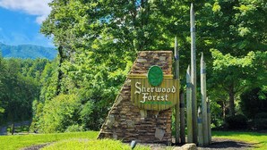 Ein Steinschild mit dem Schriftzug "Sherwood Forest Resort", umgeben von Grünpflanzen und Bäumen.